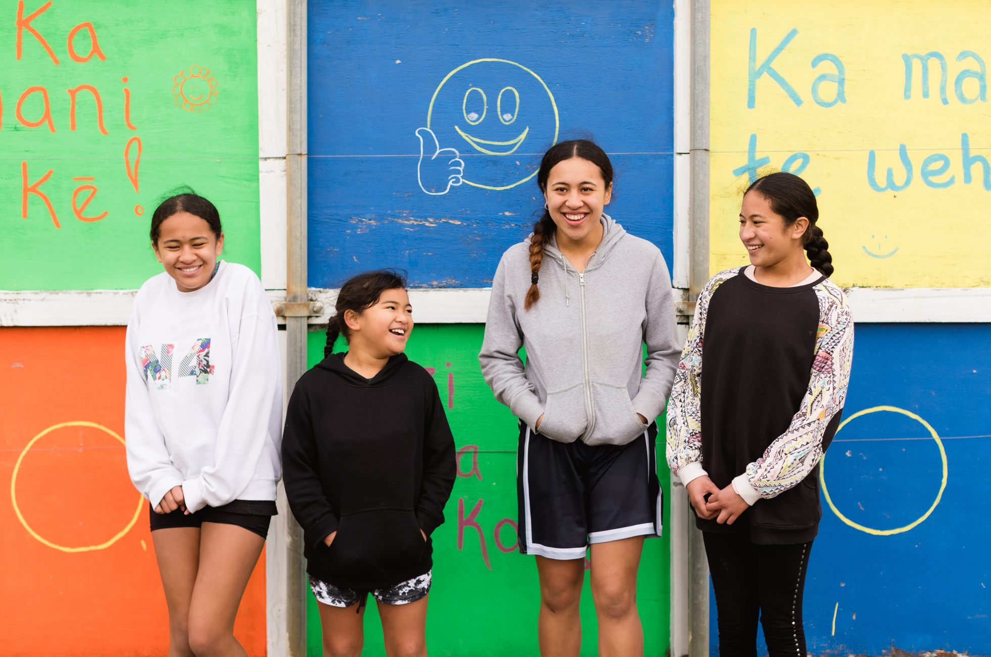 4 girls laughing in front of a colourful wall 2